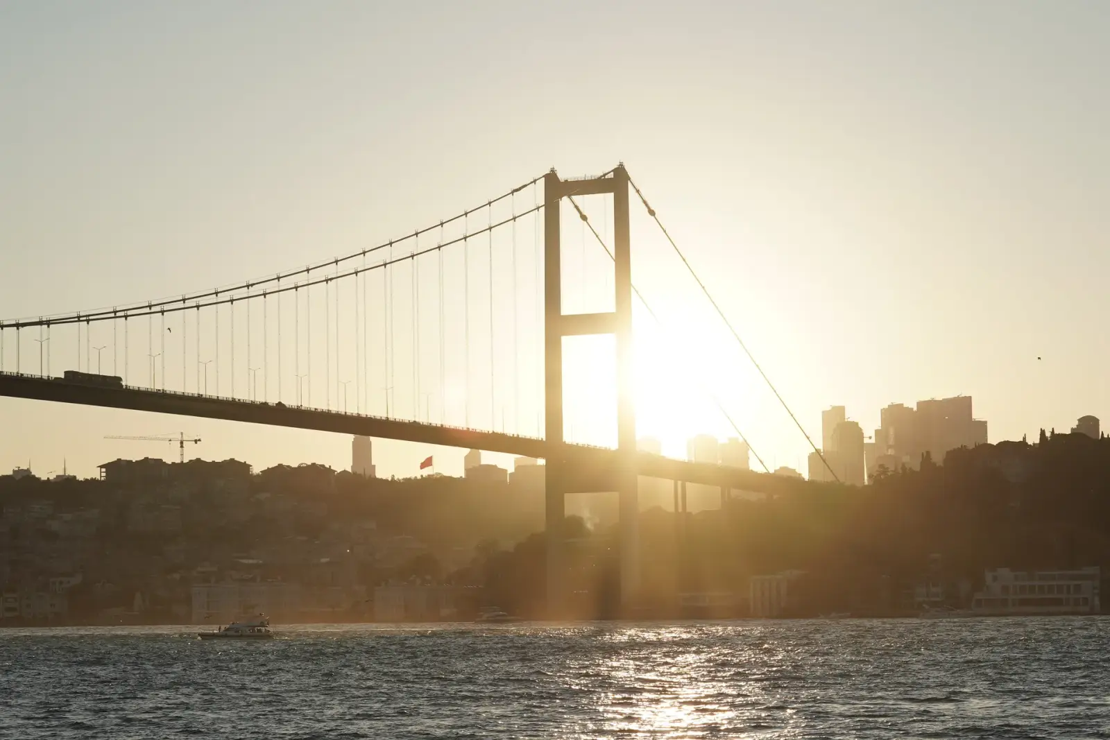 Tekneden görünen, alçalan güneşin önünde 15 Temmuz Şehitler Köprüsü